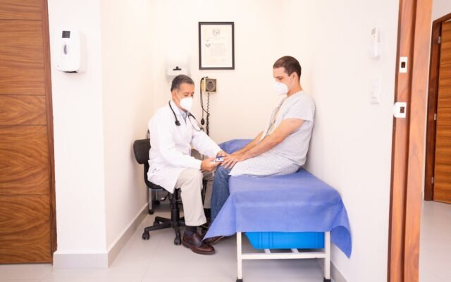 Gydytojas tikrina paciento gyvybinius požymius klinikoje konsultacijos metu