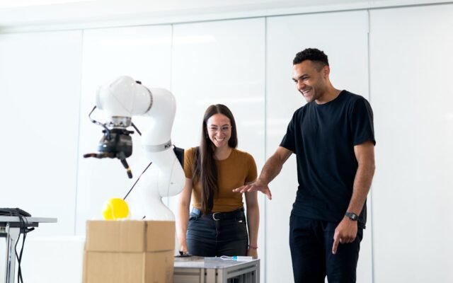Du inžinieriai kartu testuoja futuristinį roboto prototipą modernioje laboratorijoje