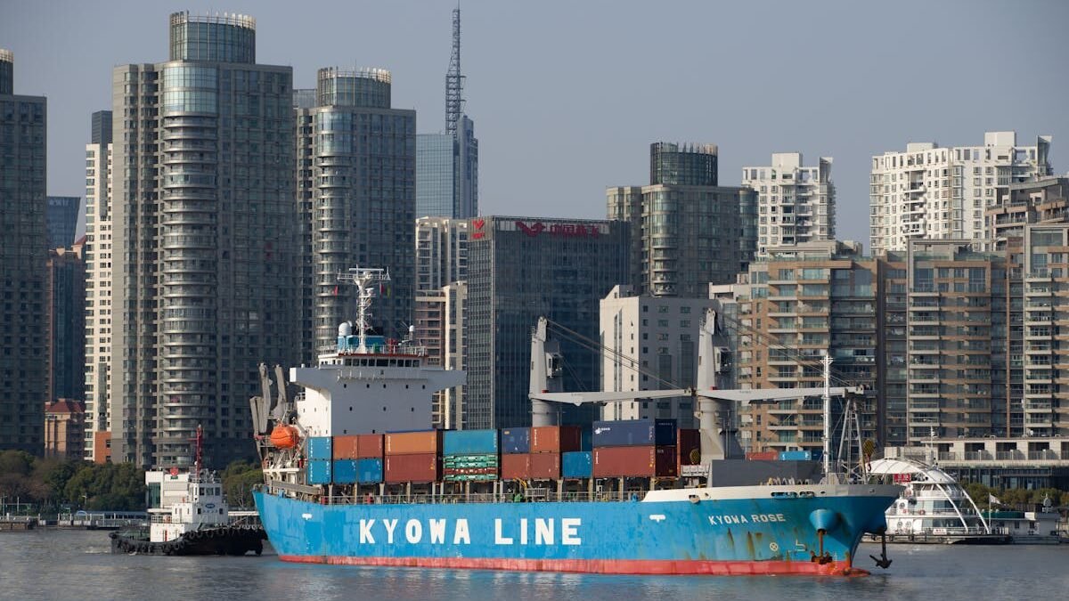 Mėlynas konteinerinis laivas modernaus miesto panoramos fone