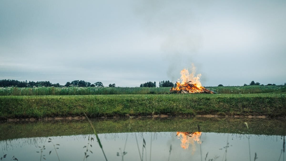 Ramus vaizdas su dideliu laužu prie tvenkinio kaimo laukuose