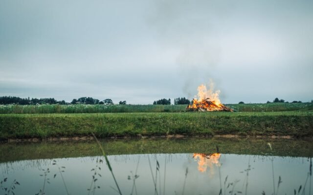 Ramus vaizdas su dideliu laužu prie tvenkinio kaimo laukuose