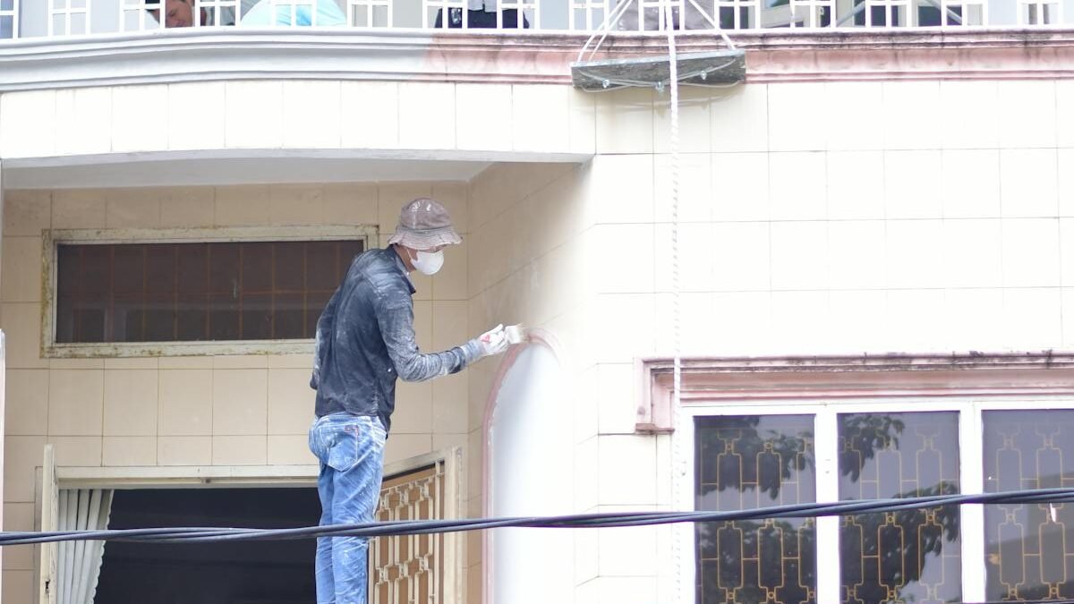 Statybininkai dažantys ir renovuojantys pastato fasadą lauke dienos metu