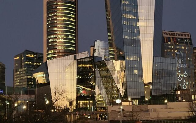 Užburianti Vilniaus dangoraižių nuotrauka sutemose su vaikščiojančiais žmonėmis